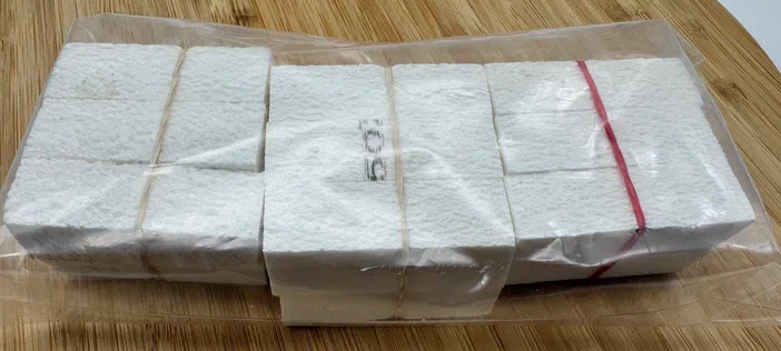 Quelques bâtons de moëlle de sureau synthétique emballés dans du plastique sur une surface en bois.