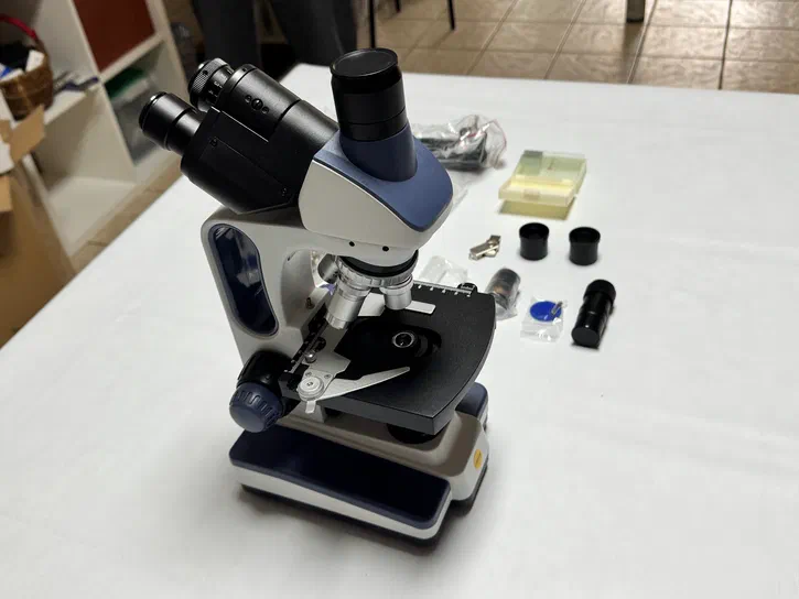 Vue d'ensemble du microscope Vue d'ensemble du microscope Swift SW350T avec ses accessoires disposés sur une table blanche.